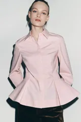 Camisa de popelín de algodón con cuello solapa, manga larga con puños y bajo con diseño peplum. Presenta cierre frontal con botones ocultos por solapa.