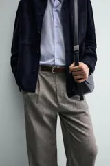 Pantalón relaxed fit color marrón con patrón de espiga, confeccionado en tejido con viscosa. Presenta pliegues frontales, bolsillos laterales y bolsillos traseros de vivo. Cierre frontal con cremallera y botón.