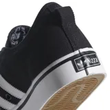 Championes Adidas Nizza de corte bajo, confeccionados en lona negra con las tres bandas laterales en blanco. Presentan puntera de goma reforzada y suela vulcanizada blanca con detalle de línea negra.
