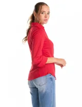 Camisa entallada de color rojo, con cuello solapa, escote en V y cierre frontal con botones. Presenta una pechera con alforzas horizontales y mangas tres cuartos con puños anchos rebatibles.