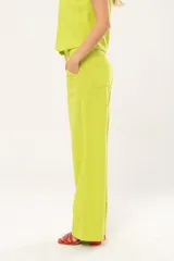 Pantalón verde lima de lino imperial con lurex, tiro medio, corte palazzo, bolsillos delanteros y traseros, cierre frontal con cremallera y botón.