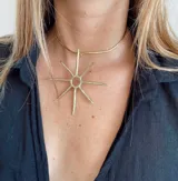Gargantilla dorada rígida con dije en forma de sol con rayos puntiagudos.