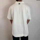 Chomba negra de corte oversize con cuello polo y tapeta de dos botones. Tejido de punto acanalado vertical.