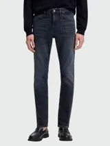 Jean de corte slim-fit en denim azul oscuro con efecto desgastado, cierre de botón y cremallera, y diseño de cinco bolsillos.