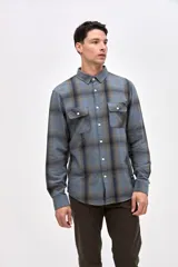 Sobrecamisa de algodón con diseño a cuadros en tonos azules, cuello clásico, cierre frontal con botones y dos bolsillos en el pecho con solapa.