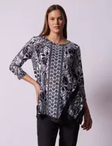 Blusa estampada en blanco y negro con diseño floral, de la marca Ruby Rd. Tiene cuello redondo con apliques de brillos, mangas 3/4 y ruedo asimétrico.