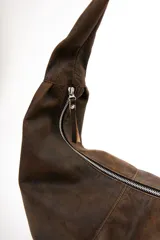 Bolso hobo marrón de cuero con correa al hombro. Diseño minimalista y amplio espacio interior.