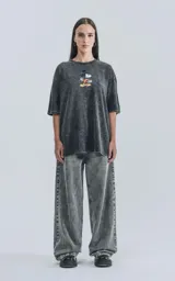 Remera de algodón premium color negro con efecto nevado (acid wash), corte oversize y cuello redondo. Presenta un estampado frontal de Mickey Mouse con una patineta.