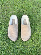 Zueco de cuero color marrón oscuro, con costuras decorativas en hilo rojo en el empeine y suela plana de goma.