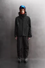 Cazadora deportiva de esquí en color negro, confeccionada en tejido técnico impermeable de tres capas con costuras y cremalleras termoselladas. Cuenta con capucha ajustable, ventilación en axilas, puños con ajuste de tira adherente y puño interior elástico con abertura para el pulgar. Incluye sistema de rescate RECCO y faldón interior para protección contra el frío.