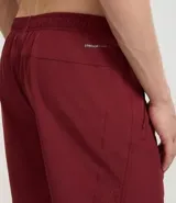 Bermuda deportiva gris con cintura elástica, cordón de ajuste, bolsillos con cremallera, recorte lateral con agujeritos y abertura en el bajo.