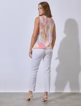 Blusa sin mangas de gasa estampada, con cuello a la base y escote en V. Presenta detalles calados en la delantera, abertura central con botones y terminación anudada.