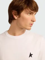 Remera de algodón blanca con cuello redondo y manga corta, presenta una pequeña estrella negra estampada en el pecho.