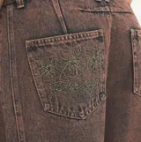 Pantalón de jean estilo barrel con efecto acid wash en tonos marrones y rosados, tiro medio y corte holgado en las piernas.