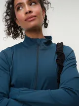 Campera deportiva marrón con cuello alto y cierre frontal completo. Presenta mangas largas con orificio para el pulgar y corte ajustado.