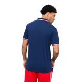 Remera tipo chomba de la marca Umbro, correspondiente al Club Nacional de Football. Es de color azul marino, con cuello polo y detalles en blanco y rojo en el borde del cuello y las mangas. Presenta el logo de Umbro bordado en el lado derecho del pecho y el escudo del club en el lado izquierdo.