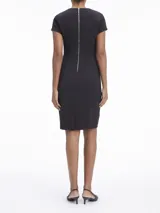 Vestido negro de corte ajustado, con largo a la rodilla, mangas cortas y cuello redondo. Presenta un cierre de cremallera en la parte posterior y recortes en los hombros.