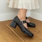 Zapato estilo Mary Jane de cuero vacuno con acabado brillante, punta cuadrada y taco bloque. Cuenta con una tira ajustable sobre el empeine con hebilla metálica.