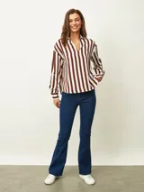 Blusa de color blanco con cuello en V y mangas largas con puños abotonados. Presenta un diseño de corte recto y holgado.