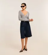 Blusa negra de punto acanalado, con escote en V profundo y mangas largas.