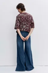 Remera de corte oversize color marrón con estampado tipo bandana en color blanco. Presenta cuello redondo y mangas cortas amplias.