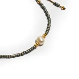 Pulsera elástica con cuentas cúbicas color gris plomo, cuentas doradas y una perla central.