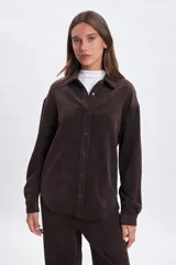 Sobrecamisa de pana en color marrón, con cuello clásico, cierre frontal con botones a presión y mangas largas con puños abotonados.
