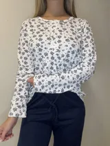 Pijama de algodón compuesto por una remera manga larga con estampa floral, cuello redondo y cierre frontal de botones, y un pantalón liso.