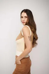 Chaleco de punto sin mangas con escote en V, diseño de bloques de color en tonos tierra (marrón, beige y crema) y terminaciones acanaladas en cuello, sisas y ruedo.