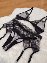 Conjunto de lencería compuesto por bralette triangular y bombacha tipo colaless, confeccionados en microtul estampado con detalles de encaje negro. Incluye portaligas desmontable con tiras ajustables.