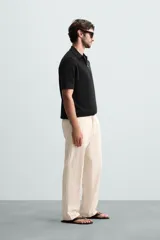 Polo de manga corta, color azul medio, tejido en punto perlado con cuello solapa y cierre frontal de cremallera.