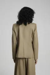 Saco negro de lana con calce entallado, cruzado con botones dorados con pie en delantero y bolsillos sastreros en delantero con tapa.