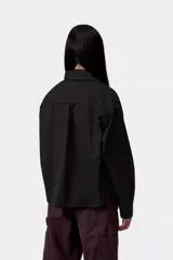 Chaqueta tipo camisa Carhartt WIP modelo Kelly, de color negro, confeccionada en sarga de algodón sin forro. Presenta cierre frontal de botones, bolsillos delanteros en el pecho con solapa, cuello camisero, hombros caídos y una etiqueta cuadrada tejida de la marca.