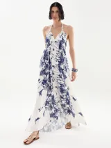 Vestido largo blanco con estampado floral azul, escote halter y corte acampanado.