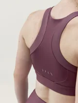 Top deportivo negro de sujeción media alta, confeccionado en tejido Shape_Tech con acabado satinado. Diseño con espalda deportiva.