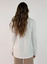 Blusa de manga larga en color blanco, con cuello redondo y detalle de alforzas verticales en el frente. Presenta un corte holgado y fluido.