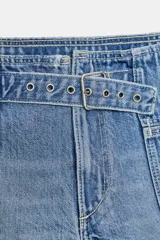 Short de denim azul claro, de tiro bajo, con bolsillos delanteros grandes y trabilla con hebilla metálica en la cintura.