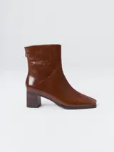Botas de caña media color marrón, confeccionadas en cuero con acabado brillante. Presentan punta cuadrada, taco de madera y un distintivo bordado decorativo en color rojo que recorre el empeine hasta la punta.