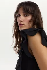 Blusa blanca vaporosa con volados en los hombros y cuello redondo.
