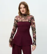 Blusa de crepé bordó sin breteles, con diseño entallado, recortes verticales y ruedo peplum con leve abertura.