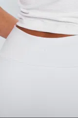 Minifalda deportiva blanca con cintura alta, calza interna y bolsillo lateral para pelota.