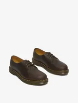 Zapato de tres ojales Dr. Martens modelo 1461, confeccionado en cuero Crazy Horse de color marrón con acabado encerado. Presenta costuras amarillas visibles en el borde de la suela y suela de goma con cámara de aire.