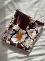 Pañuelo cuadrado de seda con estampado floral en tonos naranja, borra de vino, beige y blanco.
