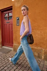 Top corto de cuello halter con diseño delantero cruzado y bajo abullonado con elástico. Presenta un estampado sutil de lunares y cierre en la espalda con botones ocultos.