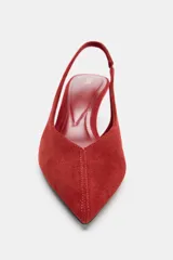 Zapato de tacón destalonado color rojo, con acabado en punta y tacón fino de 6 cm. Presenta pespunte en la parte delantera y tira trasera con pieza elástica lateral.