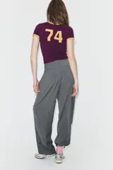 Pantalón de tiro alto con diseño de rayas verticales, corte recto y holgado. Presenta pliegues frontales, bolsillos laterales y bajo ajustable con botón.