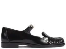 Zapato tipo guillermina Schutz de cuero negro, con diseño de mocasín, detalle de frunces en la puntera, tira con hebilla ajustable sobre el empeine y logo de la marca grabado en dorado.