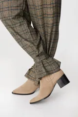 Pantalón de tiro medio con estampado a cuadros, corte holgado y pinzas en la cintura. Presenta un diseño distintivo con tiras ajustables en los tobillos que permiten crear un efecto fruncido.