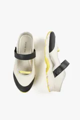 Zapato de diseño urbano color blanco con detalles en negro y amarillo, suela dentada y tira de velcro en el empeine.