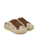 Zuecos estilo champión destalonados, con diseño estampado tipo animal print de vaca en tonos blanco, marrón y negro, pasadores marrones y suela de plataforma en tono tostado.